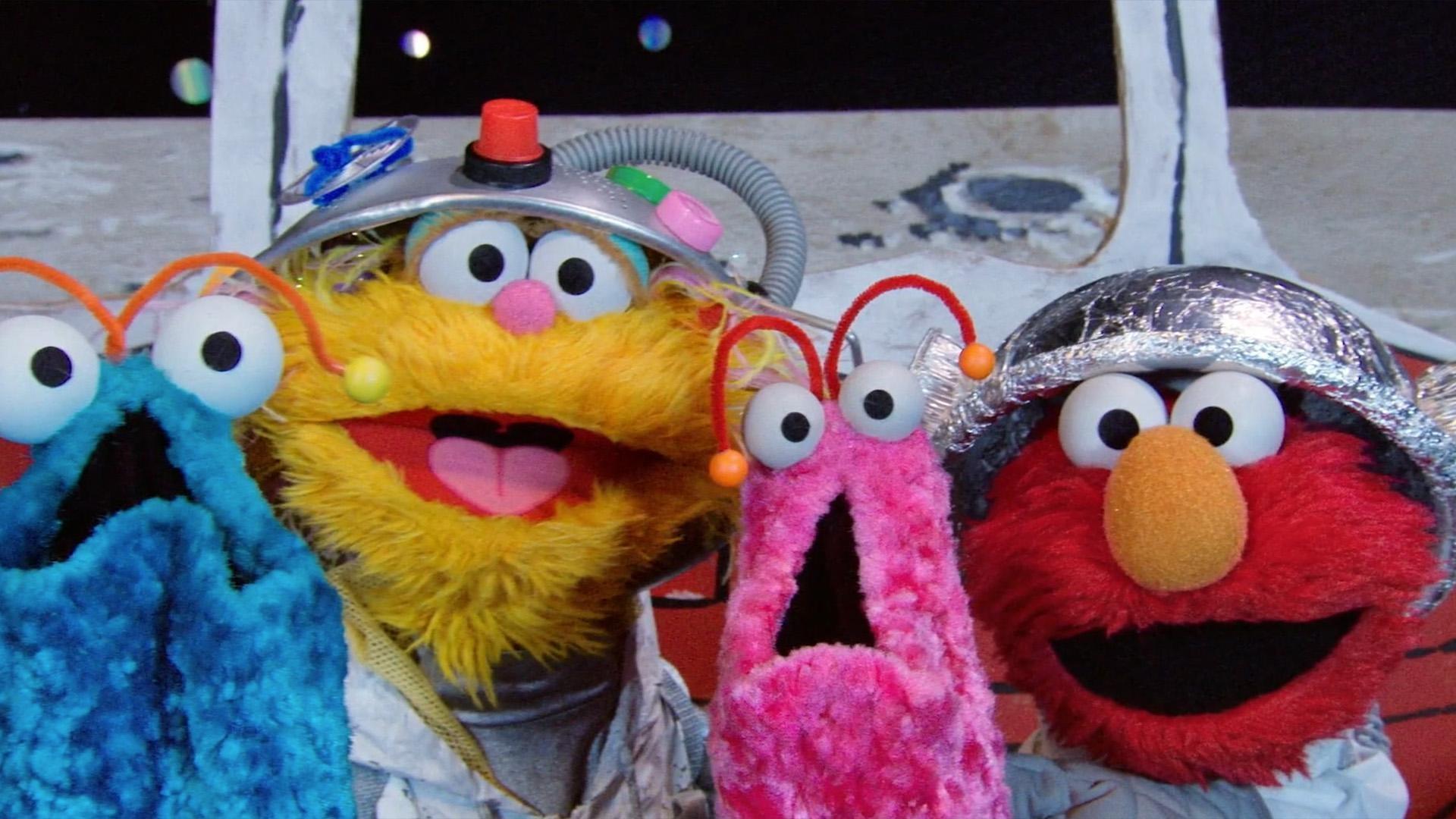 Tamir, Elmo, and Zoe pretend to be astronauts traveling to the moon.