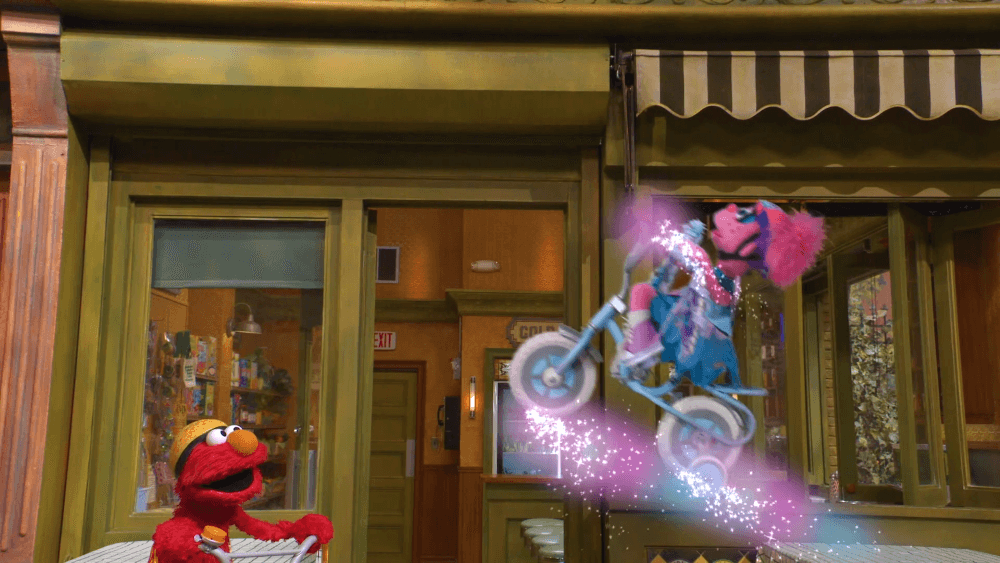 Elmo rides his new, awesome bike while Grover tries to fix Cookie Monster’s cart.